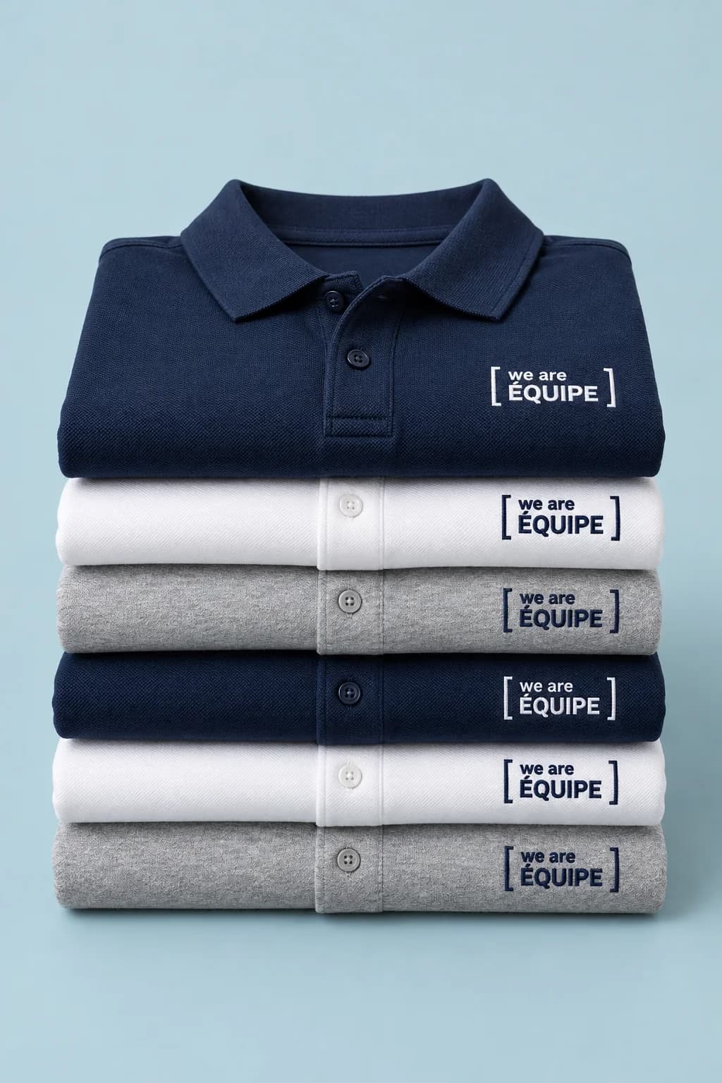 Pile de polos marine, blancs et gris, chacun brodé au cœur du cadre « we are équipe »